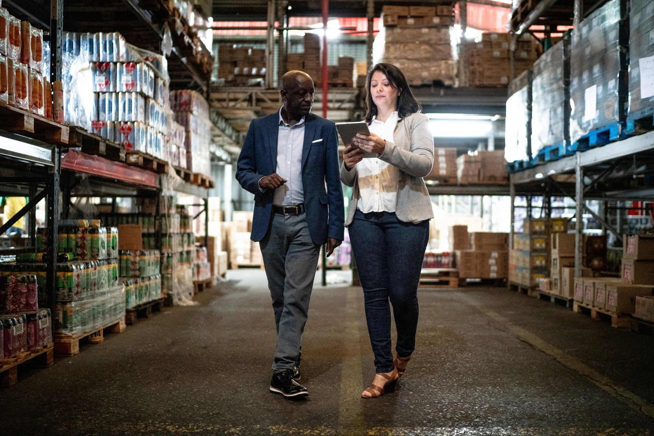 Two coworkers talking while walking through a warehouse
