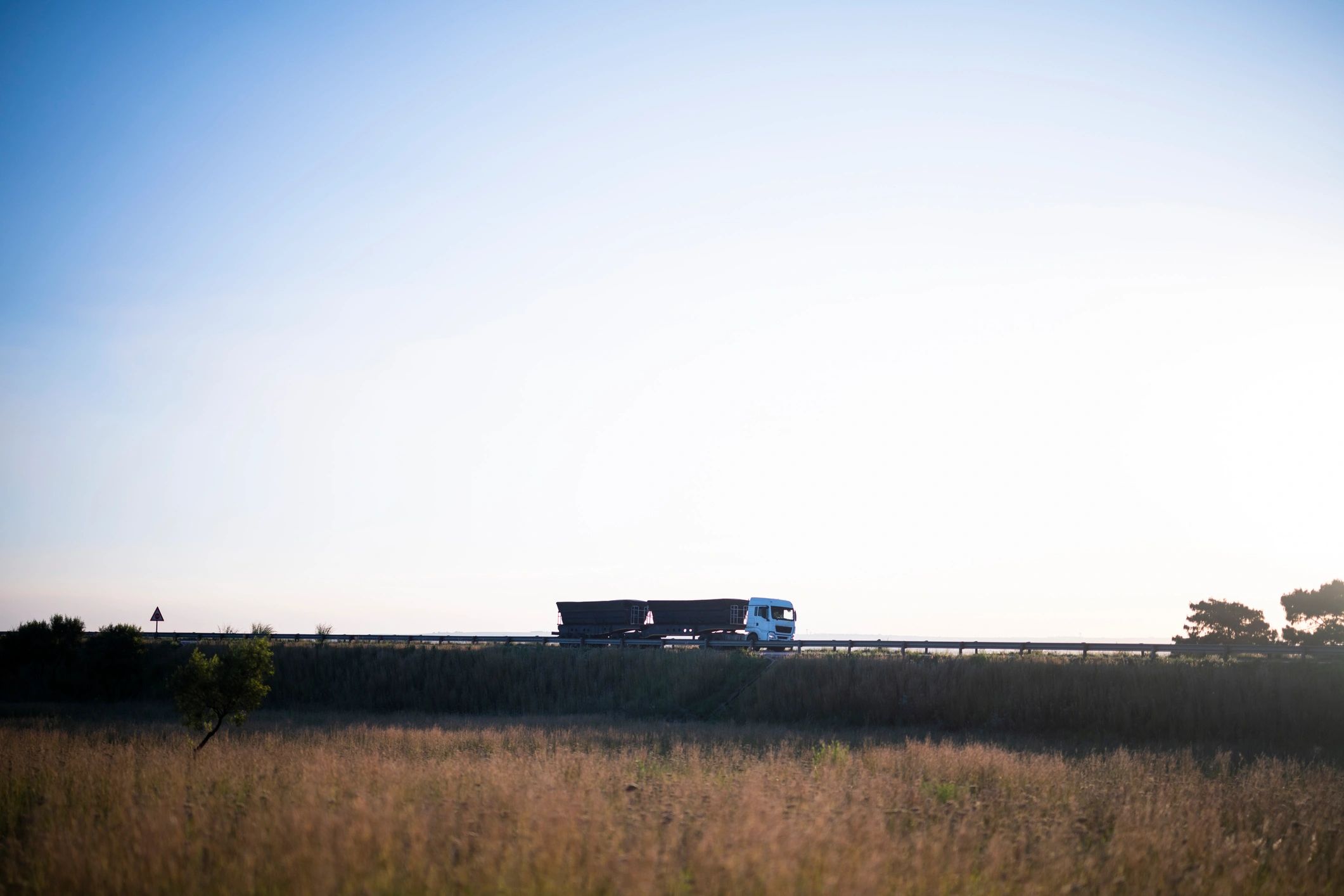 Double trailer trucks on the highway at sunrise