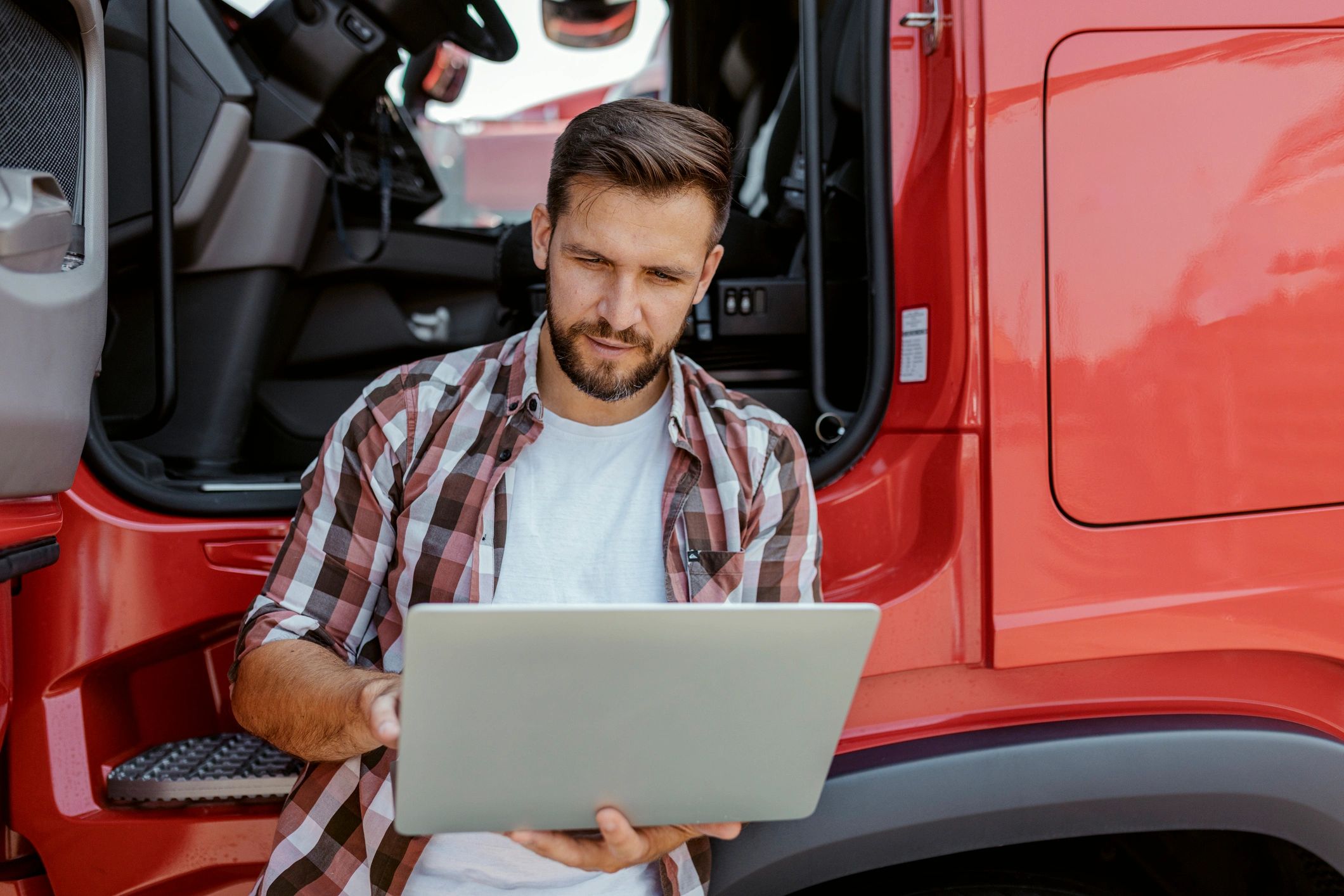 Owner-operator using a laptop beside a truck
