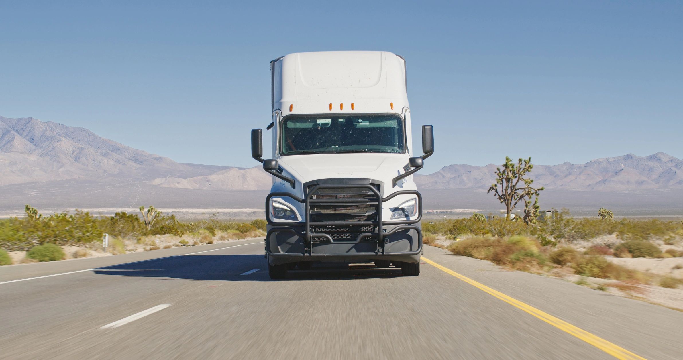 Semi-truck traveling on a highway through open desert
